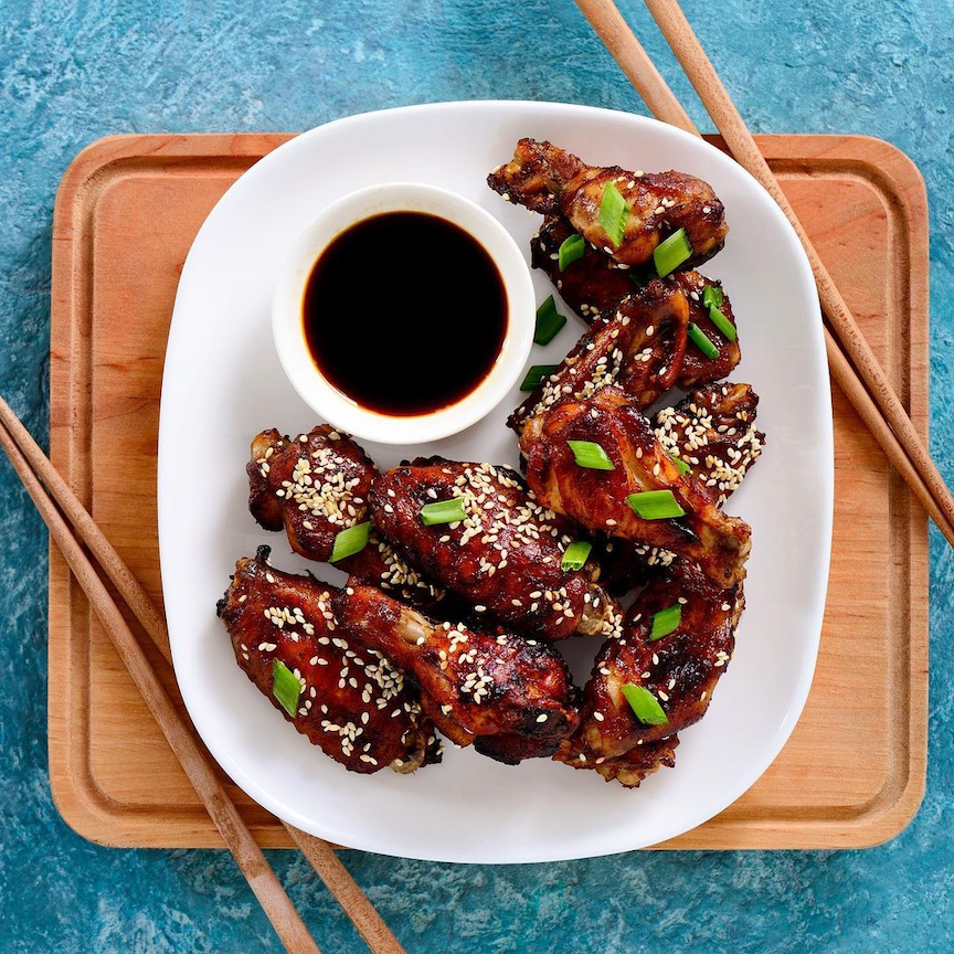 Plum Chicken wings on a plate with chopsticks.