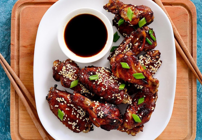 Plum Chicken wings on a plate with chopsticks.