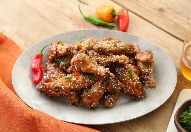 Asian chicken wings on a plate garnished with sesame seeds.