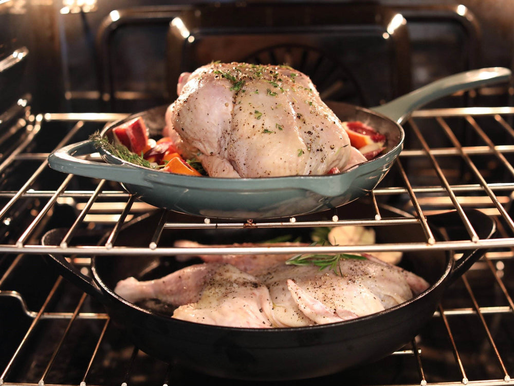 A whole chicken and chicken parts in a roasting pan in the oven with the door open.