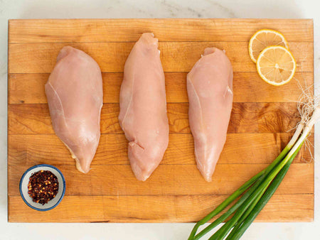 Uncooked boneless, skinless chicken breast on a cutting board.
